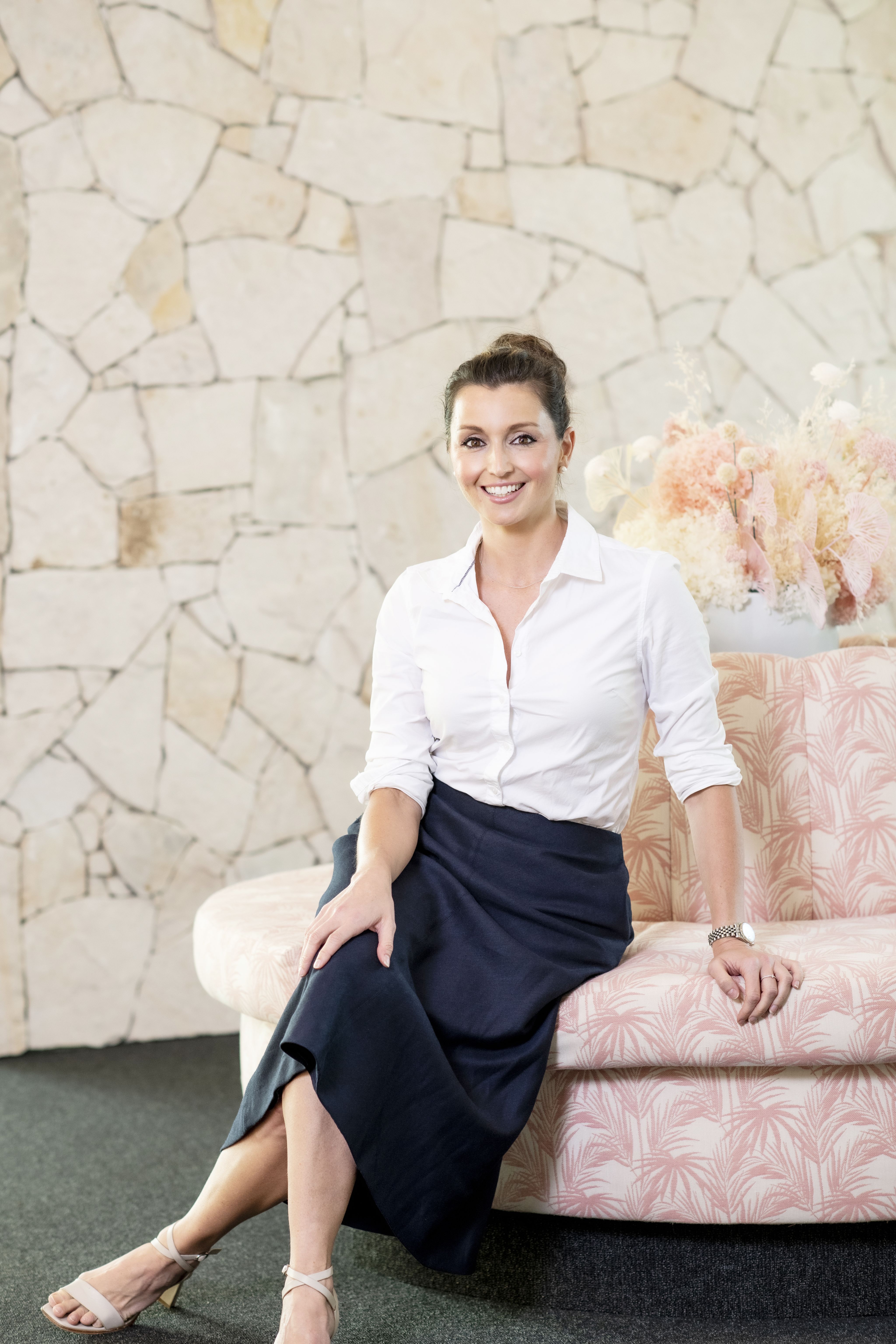 A woman is sat on a pink lounge.