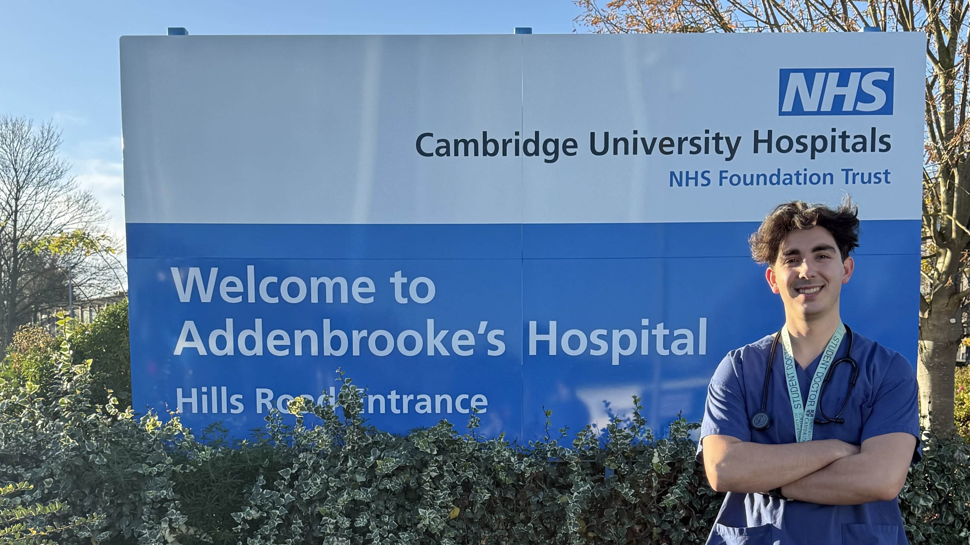 A man with his arms folded in front of a sign