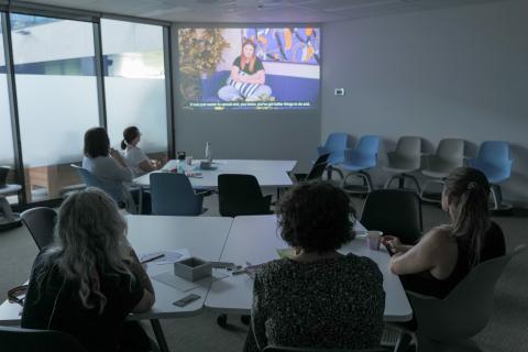 A group of study particpants watch a video projected in a classroom. 