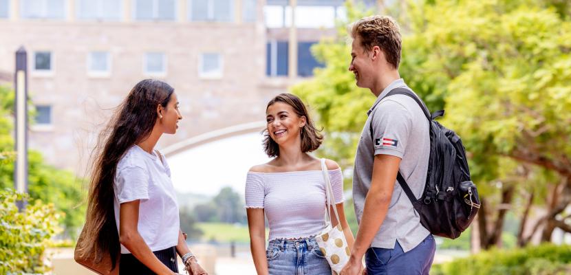 Three people standing outside in front of the Arch building.