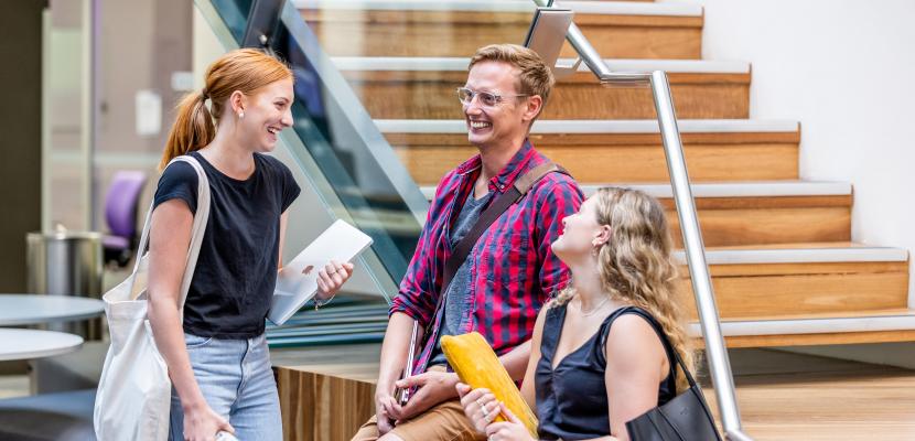 Three students cheerfully interacting in the library
