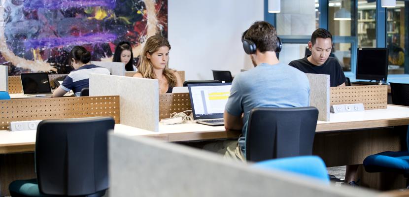 Students studying inside a Bond University library on their laptops.