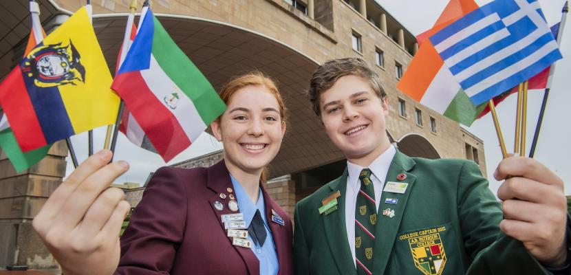 Ella Glen and Charley Ellwood standing in front of the Arch holding small flags.