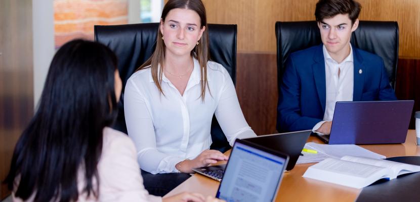 Group of students in a boardroom typing on laptops