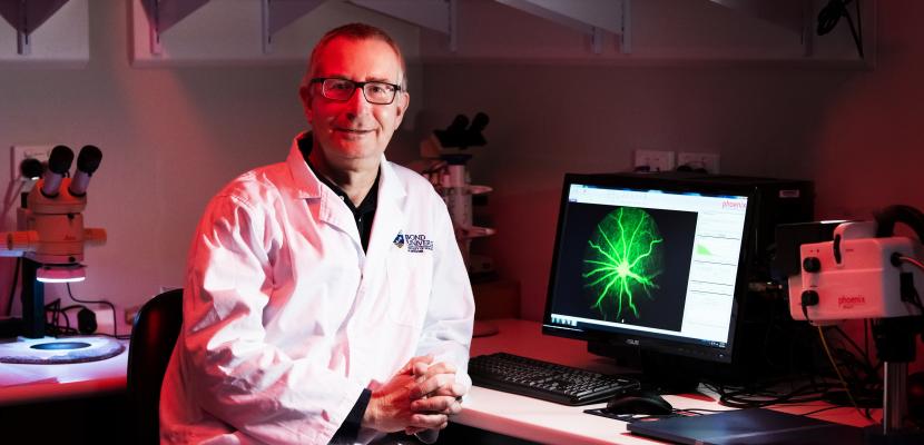 Dr Nigel Barnett in a lab coat sitting in an infrared lab