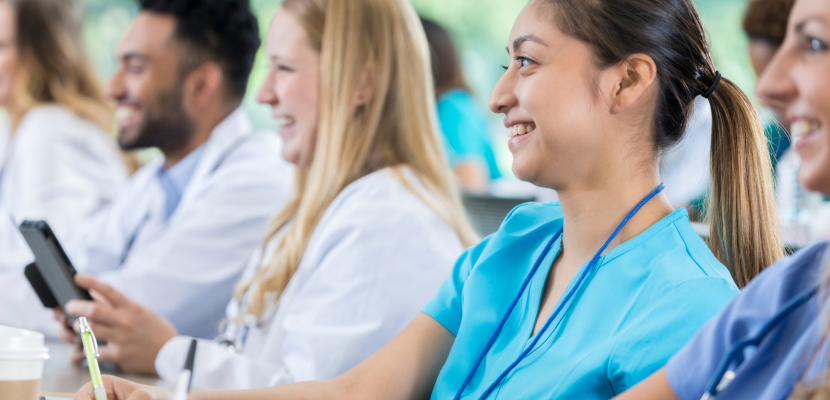 A student doctor sits in class smiling