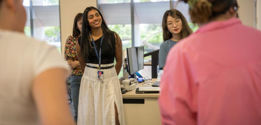 Meera Klemola stands surrounded by a few students in a Bond University classroom, smiling