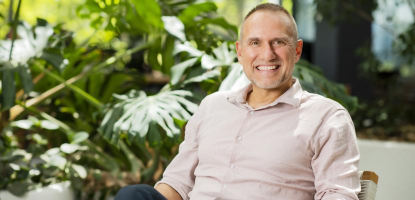 Professor Shane Hearn sitting in a chair with a plant behind him