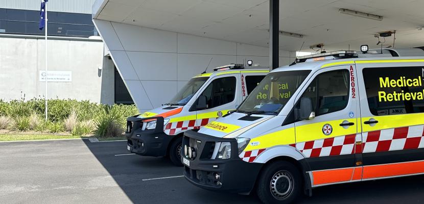 Ambulances which read "Medical Retrieval" are lined up outside an ambulance base. 