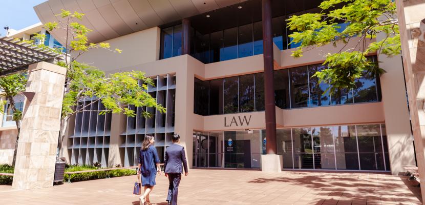 Two people are walking into the Law Building at Bond University