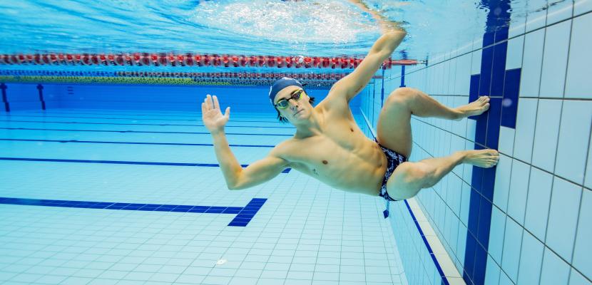 A swimmer is doing a turn under water in a pool. 