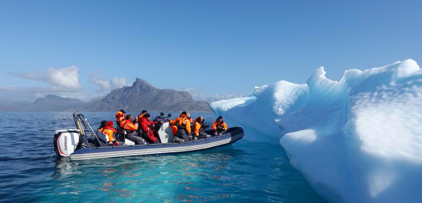 A boat full of people next to an iceberg