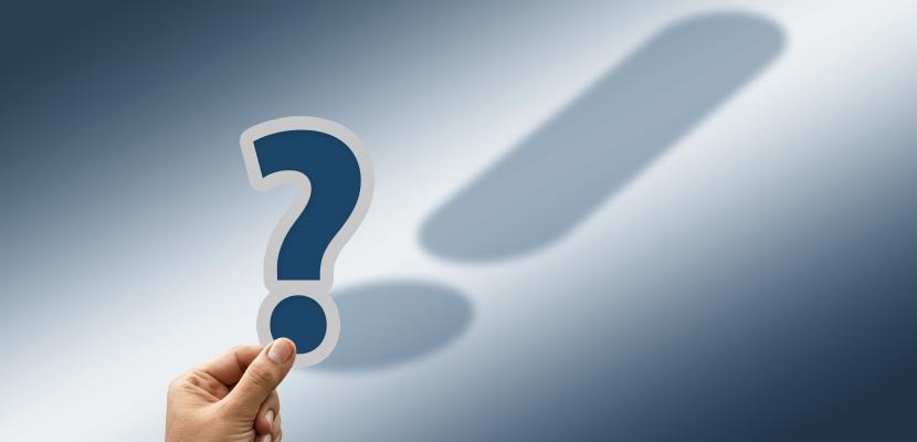 A hand holding a question mark which shadow is an exclamation mark, on a navy background 