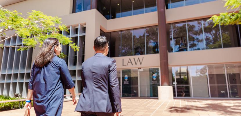 A man and a woman in suits walking into the Bond Law building