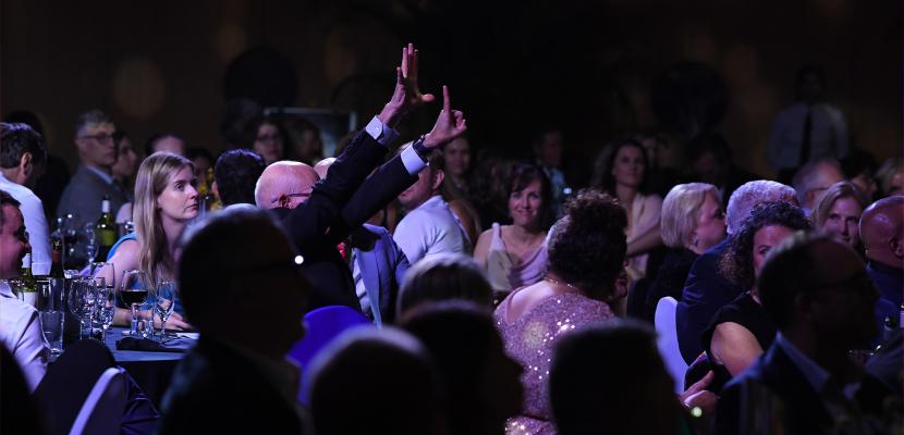 A bidder raises their hand at the Indigenous Gala