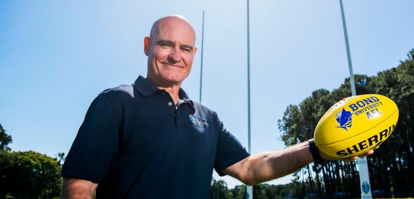 Andy Lovell holding an AFL ball on a field