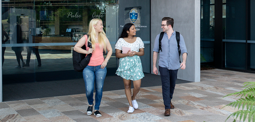 Three students walking out of the Health Sciences and Medicine building.