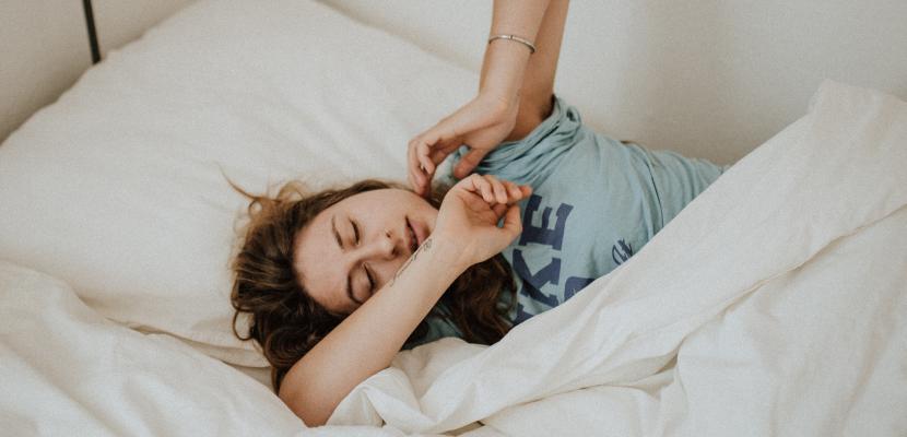 Young girl with brown hair lying uncomfortably in bed