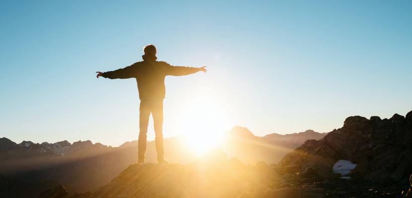 A man spreading his arms on top of a mountain