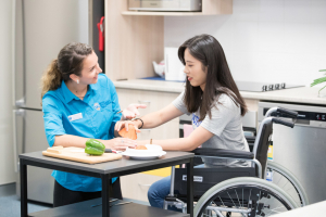 Bond University occupational therapy student sitting with a female in a wheelchair.